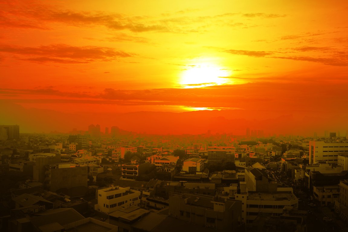 A color-treated photograph depicting a city at sunset in sweltering heat.