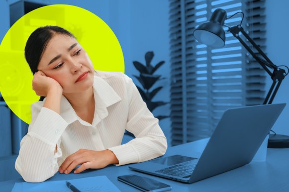 A female employee sits at her home office in front of her laptop and rests her head on one hand looking forlorn.