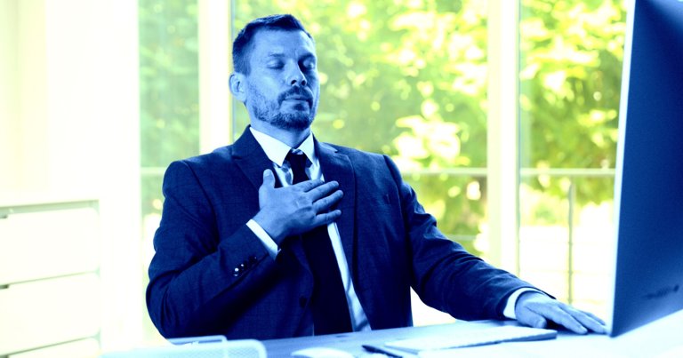 A color-treated photo of a business man holding his hand to his chest.