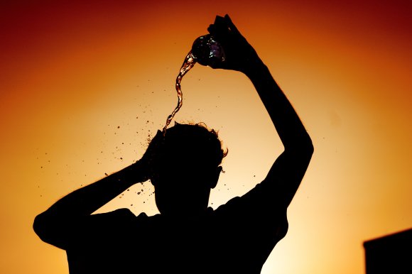 Silhouette of a person cooling down with water during an extreme summer heat wave.