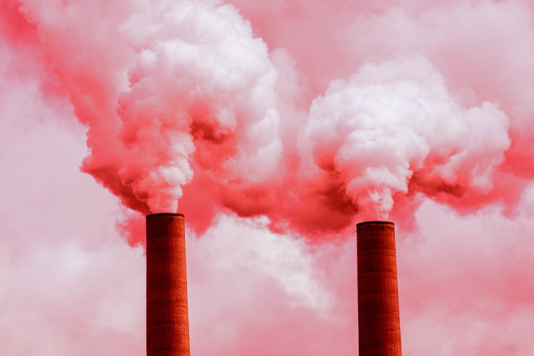 A color-treated photograph of two smoke stacks spewing pollution into the air.