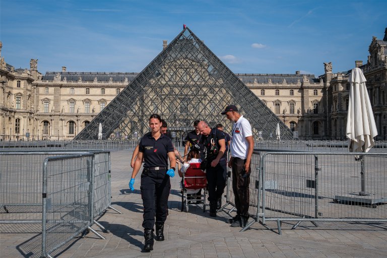 Firefighters from the Paris Fire Brigade escort a person outside the Louvre Museum during an intense heatwave in Paris, France.