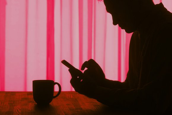 A color-treated image of the silhouette of an older man using his smartphone.
