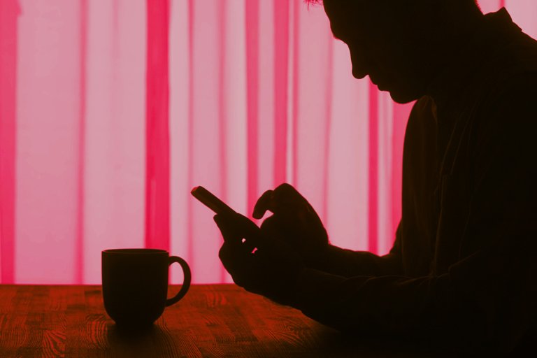 A color-treated image of the silhouette of an older man using his smartphone.