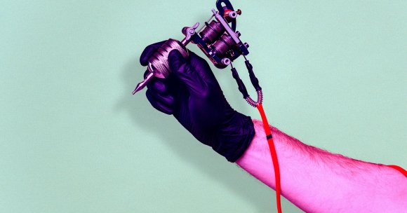 A color-treated close up of a tattooer's hand.