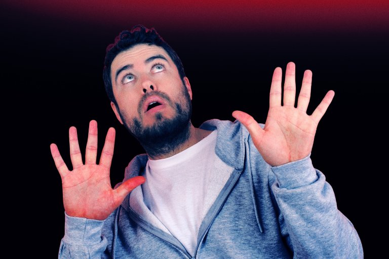 A man looks up at the sky above him with a paranoid expression on his face.