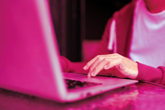 A color-treated photograph of a male student using his laptop.