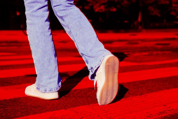 A photo illustration of a person below the waist, seen walking into the road.