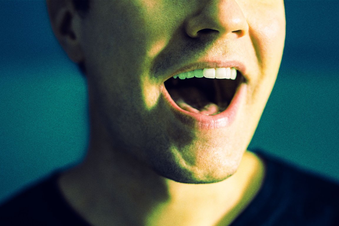 A color-treated photograph of a man's mouth as he talks enthusiastically.