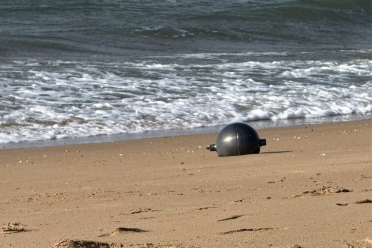 A photo from the Queensland Fire Department shows a metallic orb washed up on a beach.