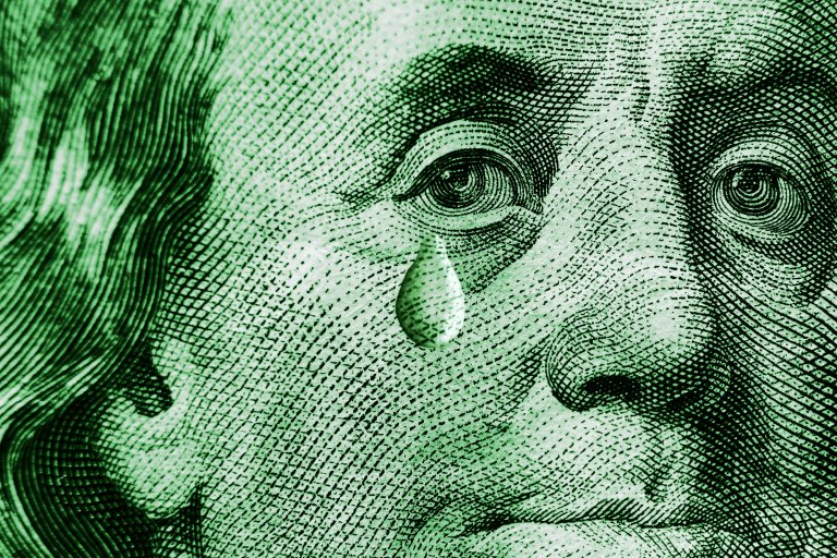 A color-treated close-up photograph of Benjamin Franklin's portrait on the U.S. $100 dollar bill. A single tear has been overlaid just underneath his eye.