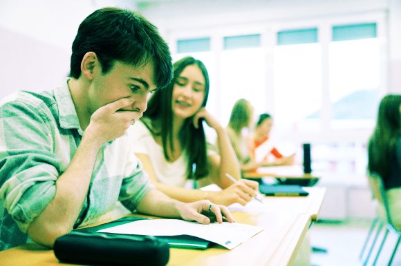 A color-treated photograph of a young male student reacting with shock to a failing grade on his paper.