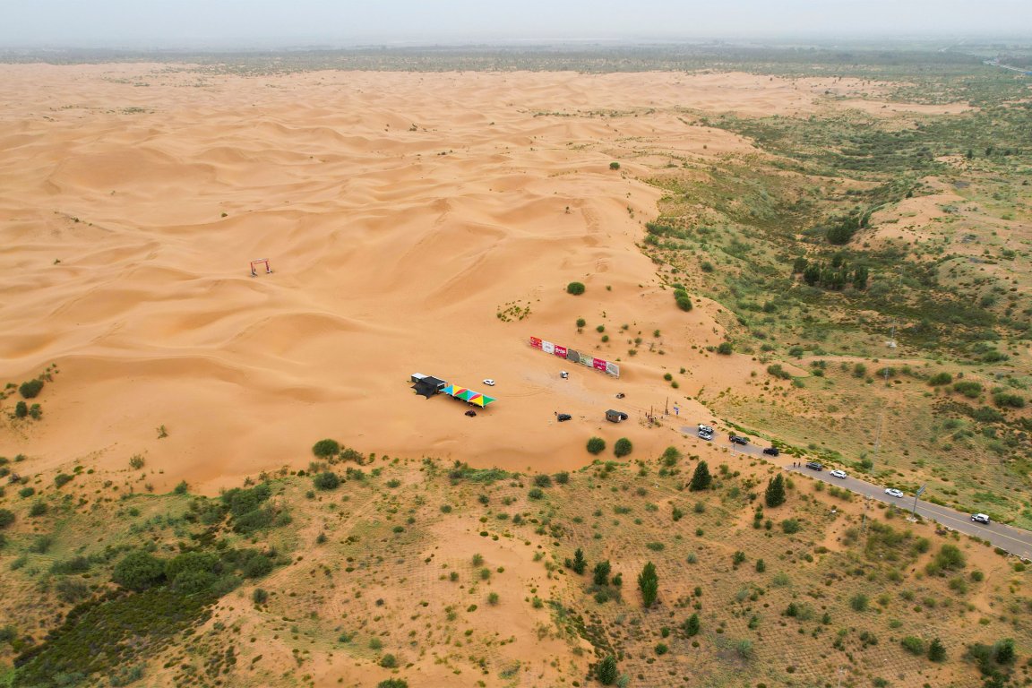 A photograph showing an aerial view of the contrast between the green zone and the desert landscape of the Kubuqi Desert, in Ordos, in China's northern Inner Mongolia region.