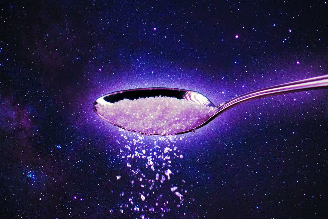 A photo illustration of space with a spoon imposed over it, full of a white granular substance.