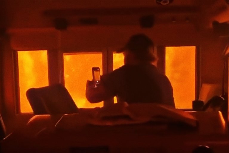 A screenshot from a video on reddit showing a man inside a train recording the fire outside.