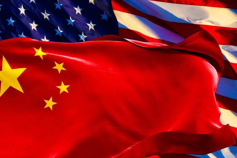 A photo illustration depicting an American flag in the background being obscured by a waving Chinese flag in the foreground.