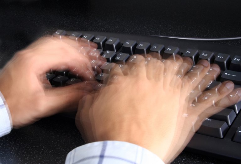 Hands on keyboard with blur effect implying that they're typing really fast.
