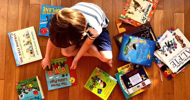 A picture of a child picking out a book on the floor.