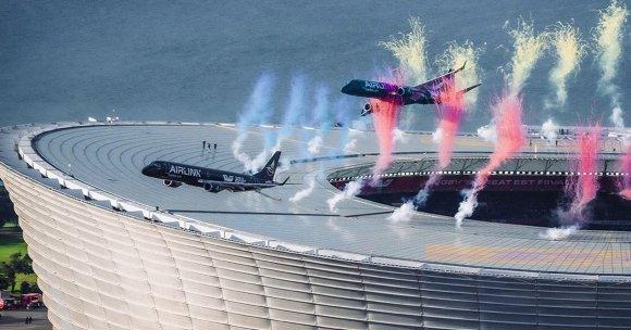 A photo showing two passenger planes flying closely over the DHL Stadium.