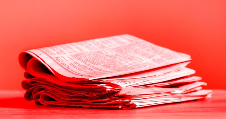 A color-treated photo of a stack of newspapers.