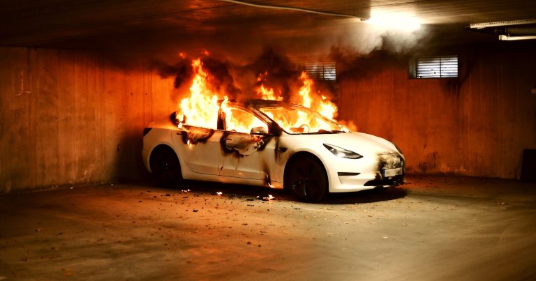 A photo showing an EV on fire inside a parking garage.