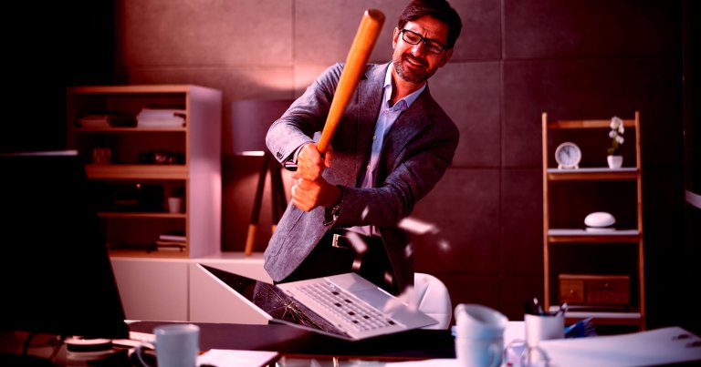 A photo of a man using a baseball bat to smash a laptop.