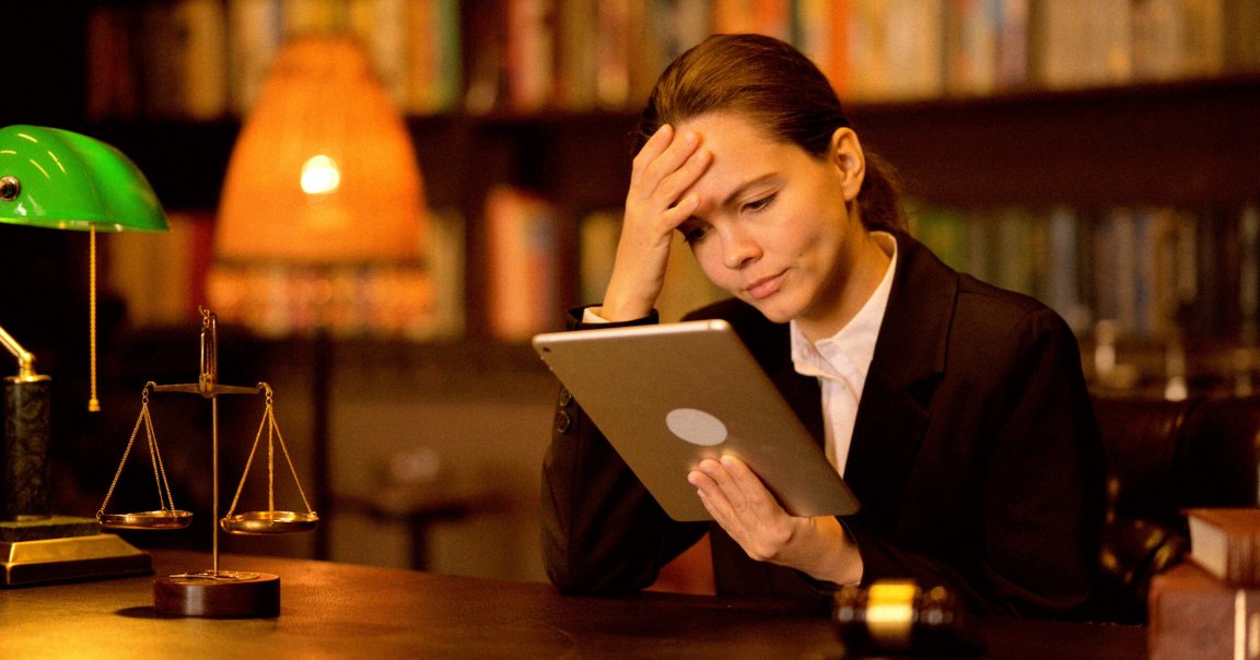 A young female lawyer reading a tablet in a courtroom.