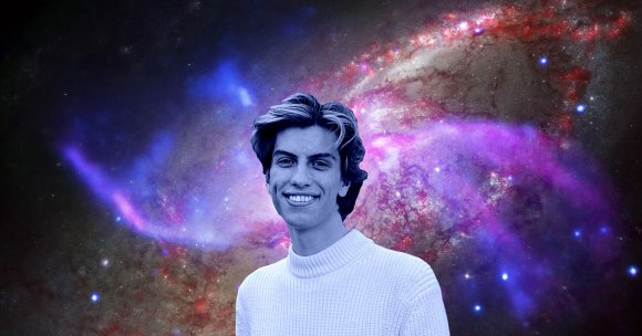 Young man with light-colored hair wearing a white knitted sweater, smiling against a vibrant cosmic background featuring colorful nebulae and stars in shades of purple, blue, and red.