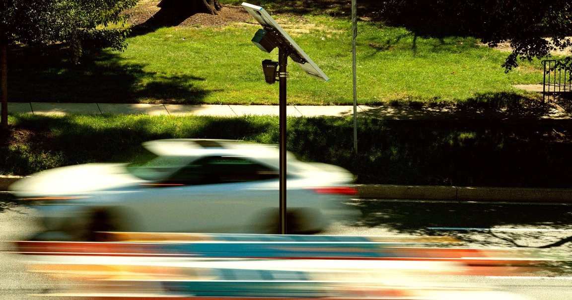 Traffic flows past an Axon brand automatic license plate reader (ALPR) camera.