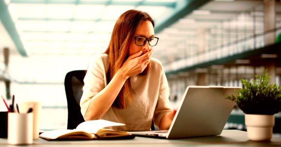 A shocked woman looking at a laptop.