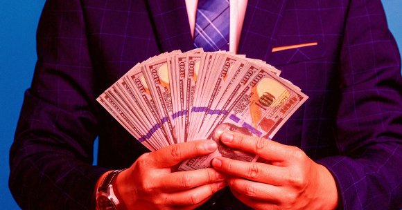 A man holding a big stack of dollar bills.
