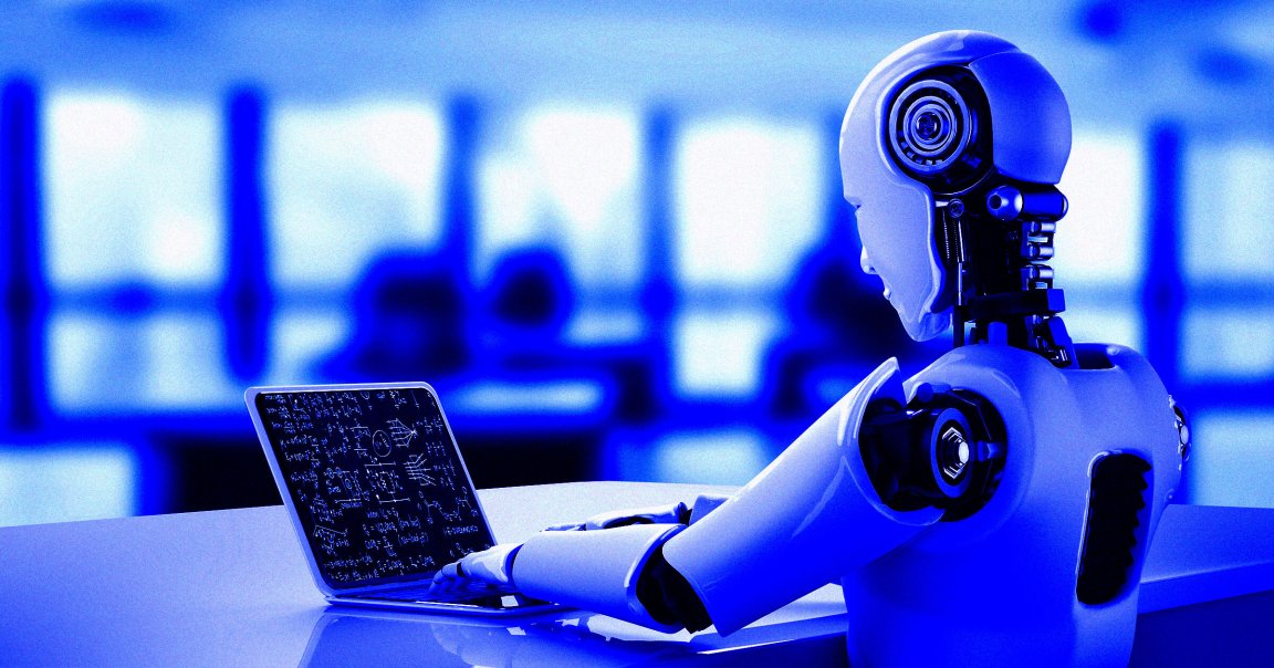 A humanoid robot sitting at a desk and looking at a laptop.