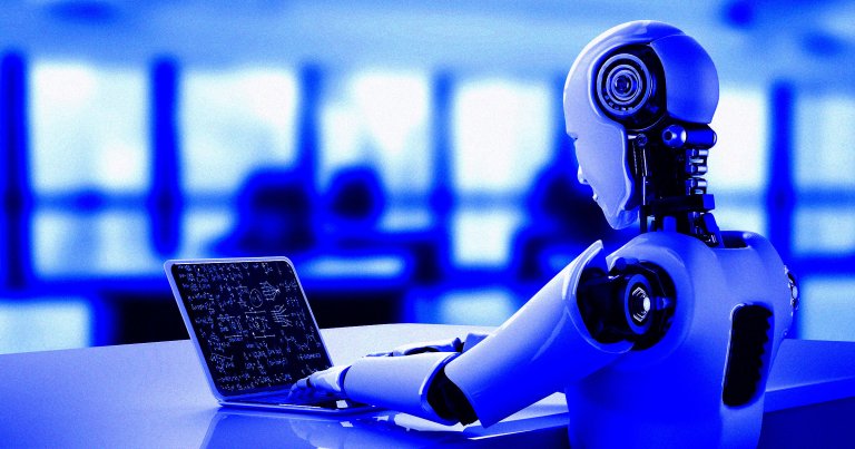 A humanoid robot sitting at a desk and looking at a laptop.