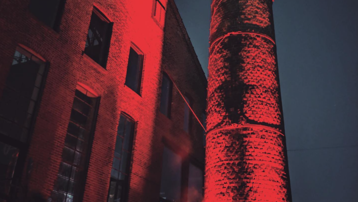 An exterior shot of Basement, a prominent NYC nightclub, featuring a warehouse-like structure and a large chimney.