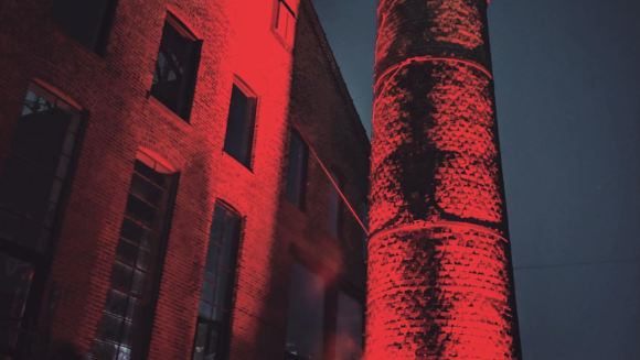 An exterior shot of Basement, a prominent NYC nightclub, featuring a warehouse-like structure and a large chimney.