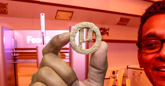 A researcher holding up a cookie made up of modified plastic waste.
