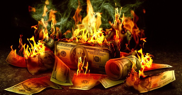 A photo illustration of a pile of money on fire.