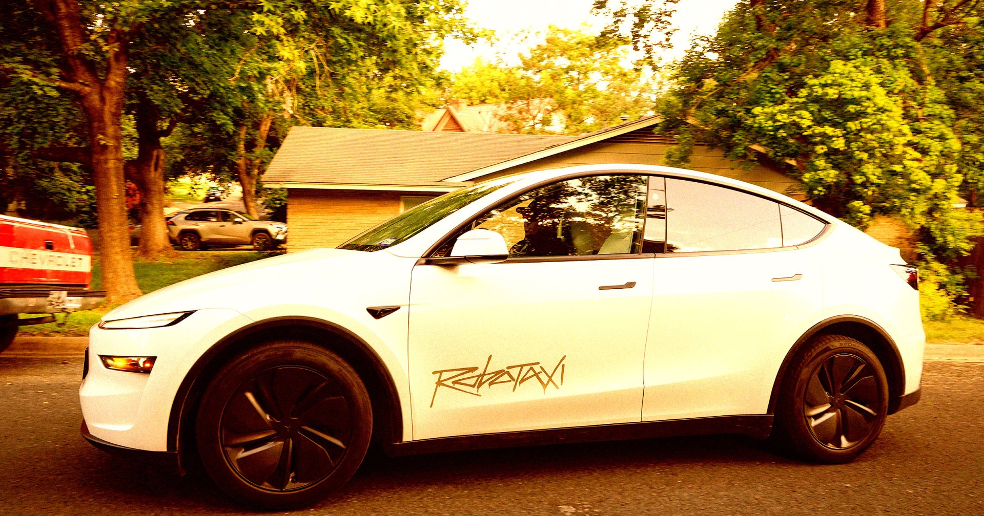 driverless Tesla Robotaxi, with a man serving as a safety monitor in the front passenger seat.
