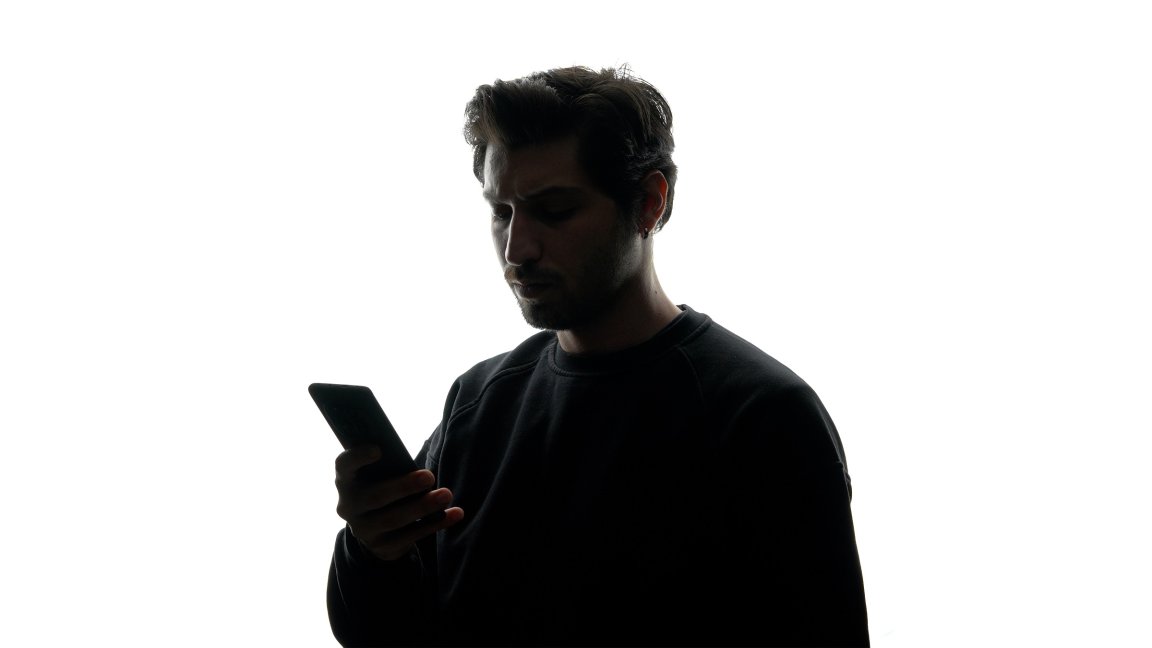 A photo illustration shows the silhouette of a man using a phone against a white background.