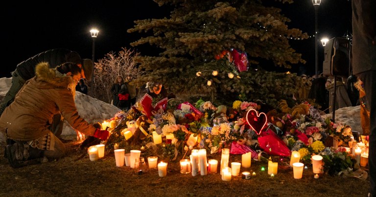 A member of the community places flowers at a memorial during a candlelight vigil for the victims of Tumbler Ridge Secondary School.