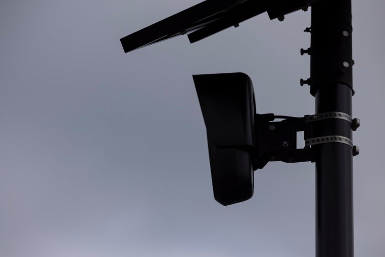 A Flock camera is shown against a gray sky.