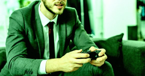 A man in a suit playing video games.