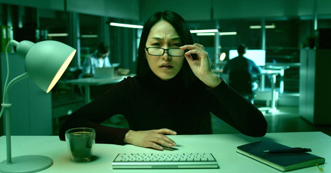 A color-treated photo of a woman reading from a computer.