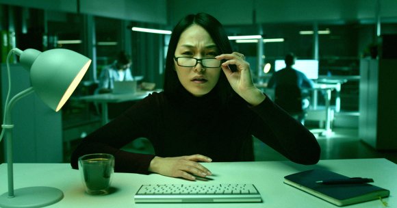 A color-treated photo of a woman reading from a computer.