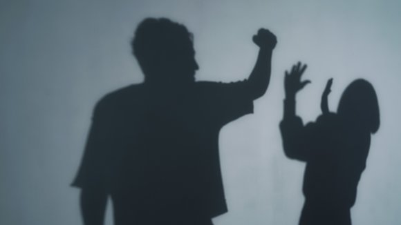 Shadows show a man menacing a woman.
