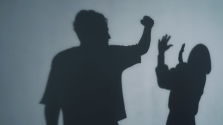 Shadows show a man menacing a woman.