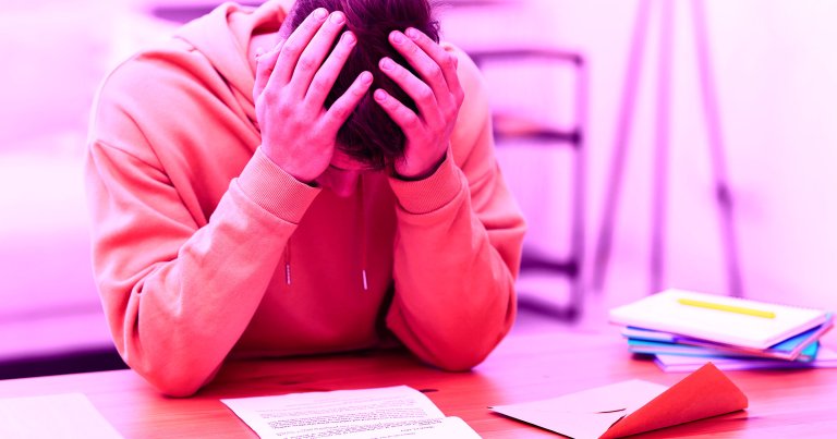 A student holding their head while looking at a piece of paper.
