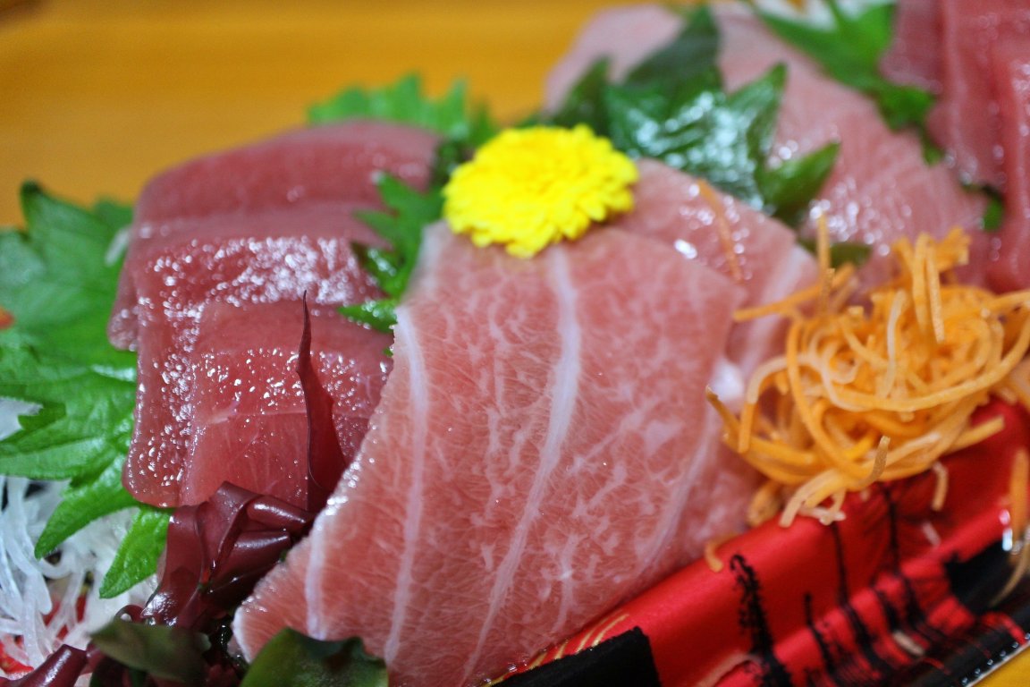 A photo shows fresh tuna sashimi on a dish with various garnishes.