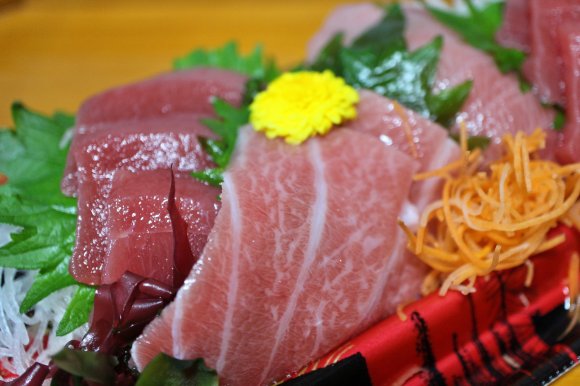 A photo shows fresh tuna sashimi on a dish with various garnishes.