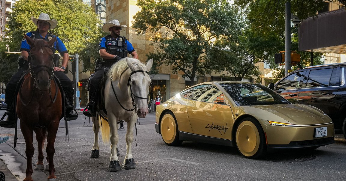 A Tesla Cybercab passes Austin Police Department officers on horses on 2nd street outside ACL Live.